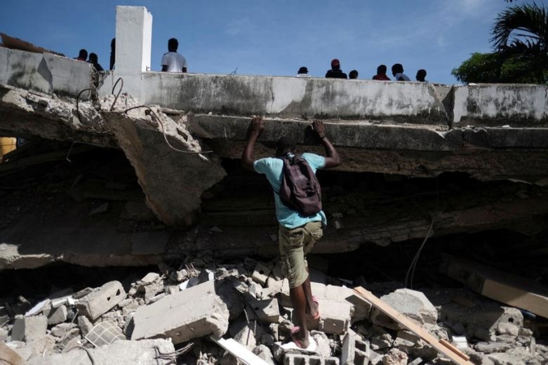 Người đàn ông tìm kiếm trong đống đổ nát một khách sạn sau trận động đất 7,2 độ ở Les Cayes, Haiti, ngày 16/8/2021.