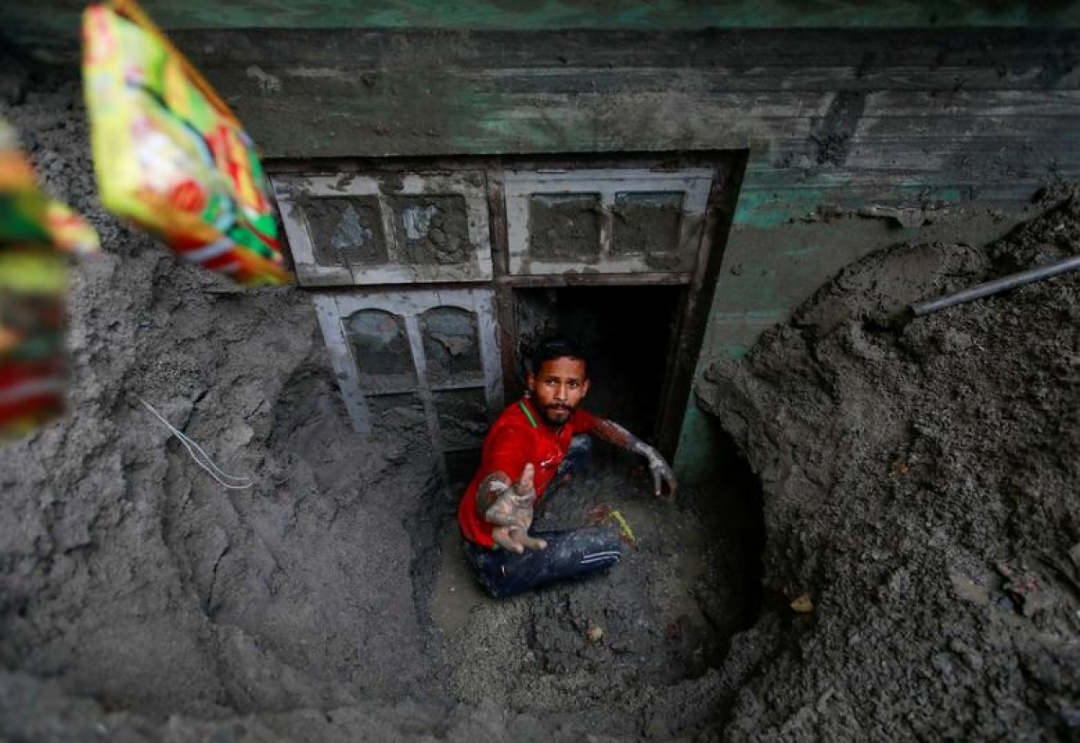 Người đàn ông đang cố tìm lại đồ đạc từ một ngôi nhà ngập trong bùn gần bờ sông Melamchi ở Sindhupalchok, Nepal, sau khi khu vực này bị lũ lut quét qua ngày 20/6/2021.