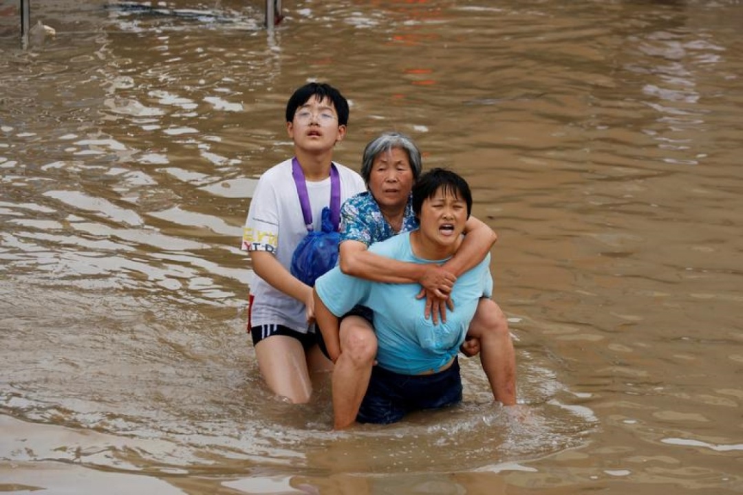 Người phụ nữ trẻ cõng một người phụ nữ lớn tuổi qua khu vực bị ngập nước ở Trịnh Châu, Hà Nam, Trung Quốc, ngày 23/7/2021.