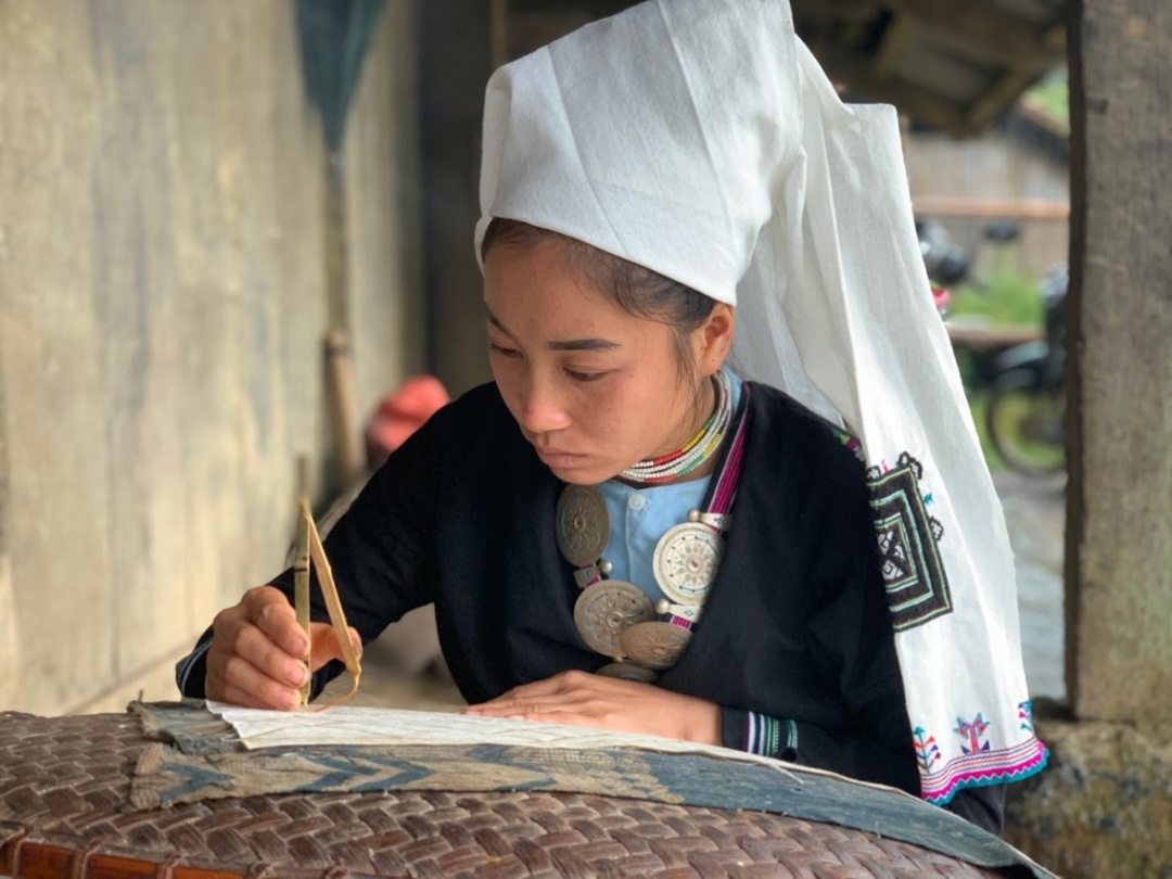 Phụ nữ Dao Tiền dùng sáp ong để in hoa văn lên trang phục truyền thống. Nguồn: Hà Cương