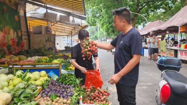 Khách mua vải Việt Nam của bà Mã Tiểu Hoa, một chủ sạp hoa quả tại phố ẩm thực Bằng Tường, Quảng Tây, Trung Quốc. Ảnh: Văn Việt.