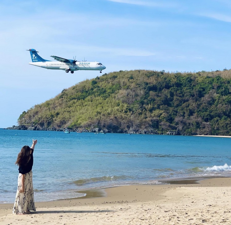 Du khách vừa ngắm biển, vừa chụp ảnh với máy bay đáp xuống sân bay Côn Đảo. Ảnh: Kim Dung