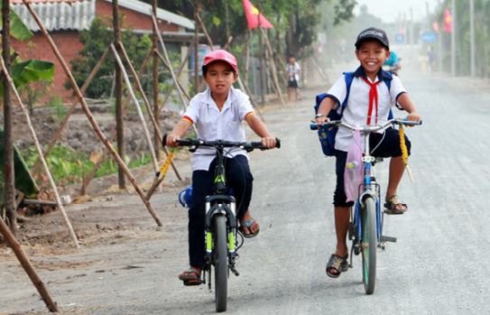 Các em học sinh đạp xe trên con đường mới.