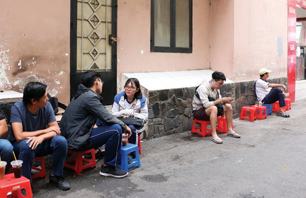 Khách uống cà phê ngồi ghế nhựa dọc con hẻm,  tán gẫu và ngắm nhìn cuộc sống thường nhật của người Sài Gòn