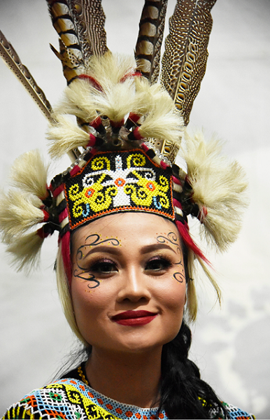 Trang sức lông chim và hình vẽ hóa trang trên mặt của cô gái vùng Kalimantan.