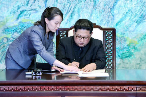 Cô Kim Yo Jong giúp anh trai khi ông Kim Jong Un ký các văn bản tại làng đình chiến Panmunjom trong khu đình chiến liên Triều ngày 27-4-2018 