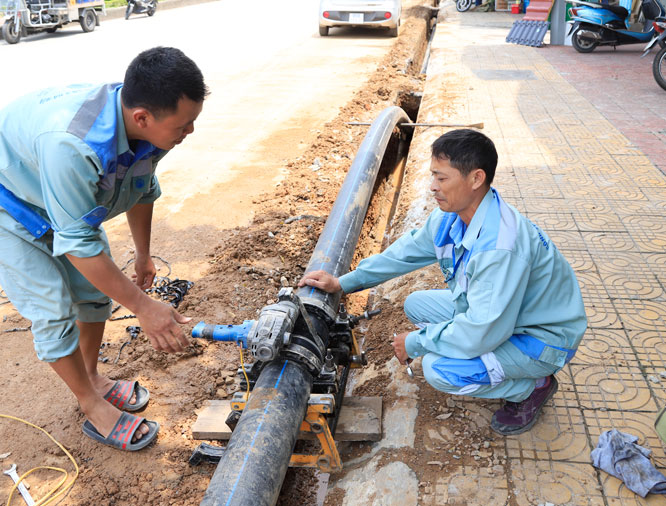 Công nhân lắp đặt đường ống nước sạch tại thị trấn Đông Anh (huyện Đông Anh). Ảnh: Nguyễn Quang.