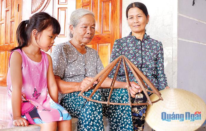 Bà Bùi Thị Xí (ở giữa) thường đem khung làm nón ra ngắm nghĩa và kể chuyện cho các cháu nghe về nghề truyền thống của cha ông.